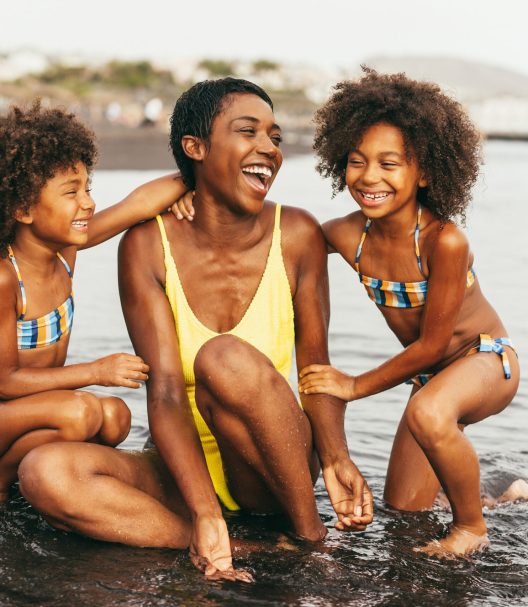 African sister twins having fun with mother on the beach - Soft focus on right girl face
